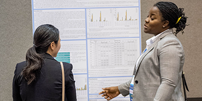 Poster presenter discussing research with meeting attendee